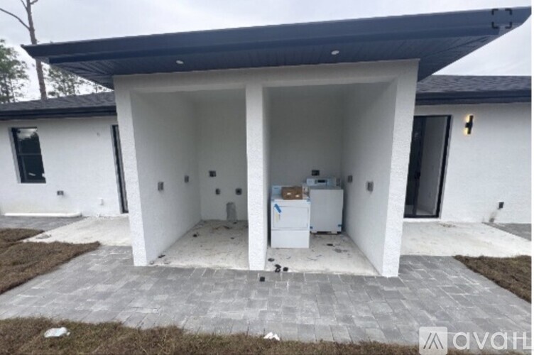 A white house with a black roof and a white refrigerator in the kitchen.
