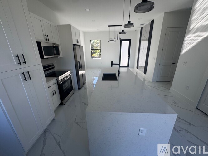 A modern kitchen with white cabinets and a marble floor.