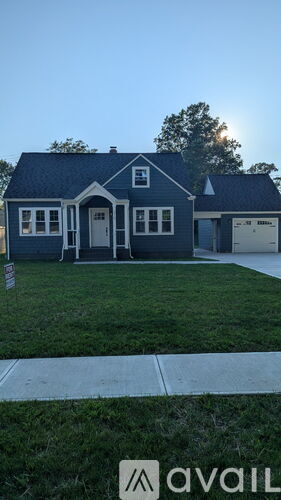 A house with a blue roof and a white garage door is for sale.