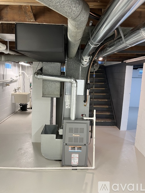 A large industrial air handling unit is installed in a spacious room with a staircase in the background.