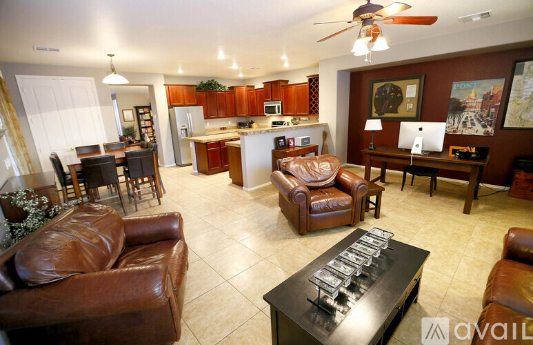 A living room with brown leather furniture and a kitchen in the background.