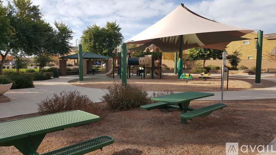 A playground with a green picnic table and a white canopy.