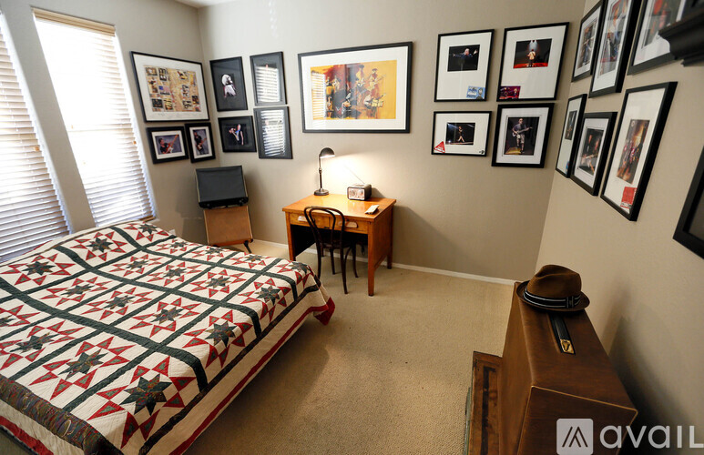 A bedroom with a bed, desk, chair, and pictures on the wall.