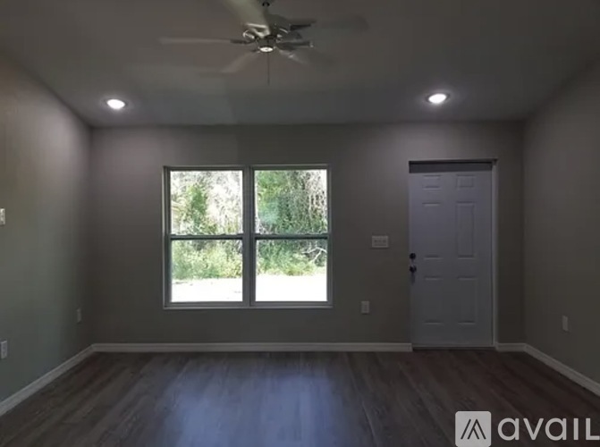 A room with a ceiling fan and a large window.