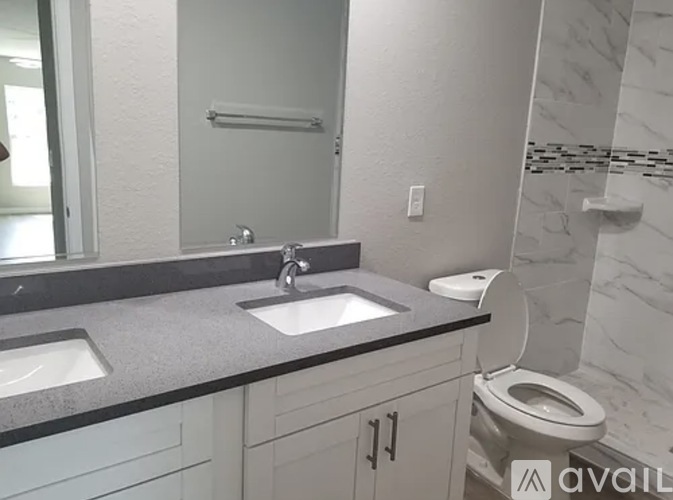 A bathroom with a toilet, sink, and mirror.