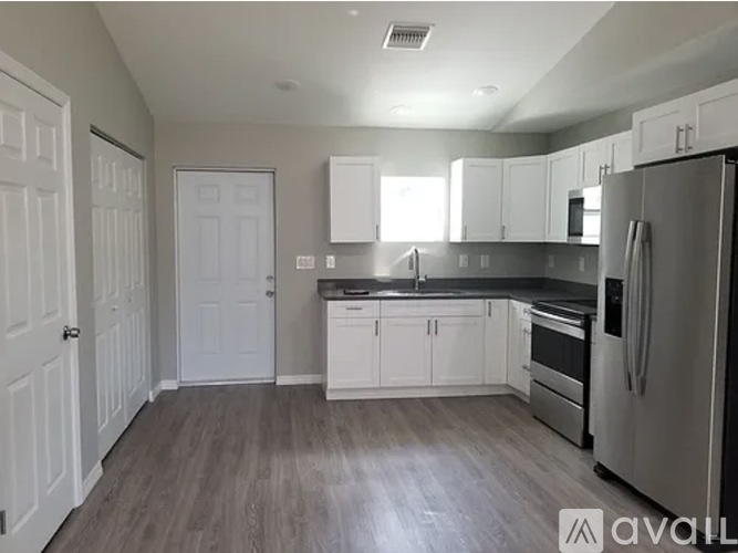 A kitchen with white cabinets and a stainless steel refrigerator.