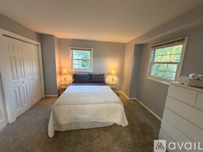 A bedroom with a bed, two lamps, and a window.