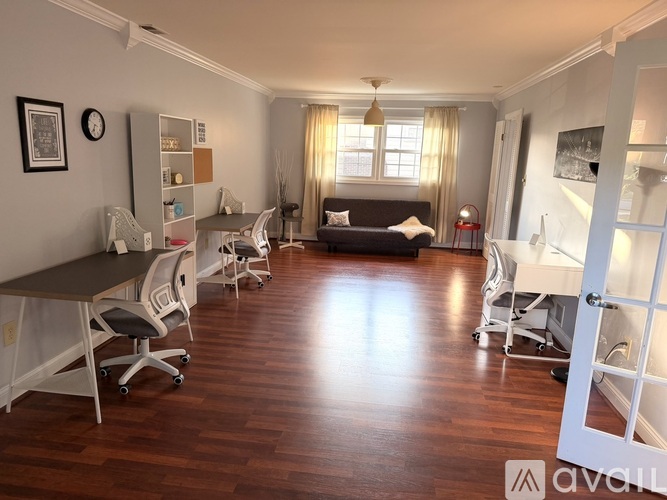 A room with a desk, chairs, and a bed.