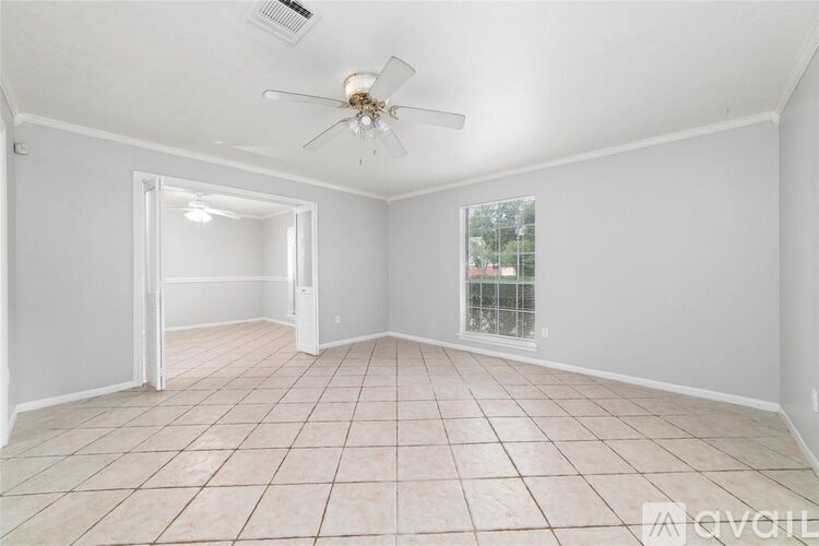 A spacious room with a ceiling fan and tiled flooring.