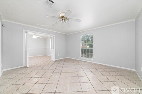 A spacious room with a ceiling fan and tiled flooring.