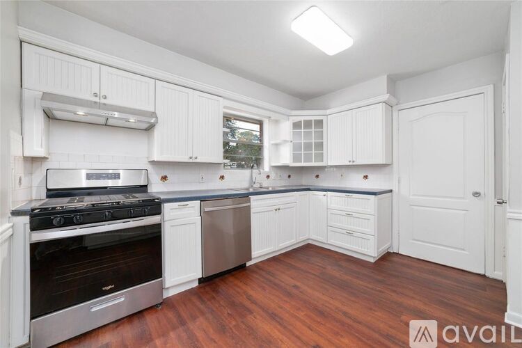A kitchen with white cabinets and a wooden floor.