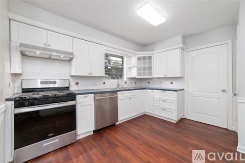 A kitchen with white cabinets and a wooden floor.