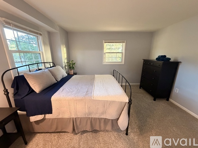 A bedroom with a bed, dresser, and window.