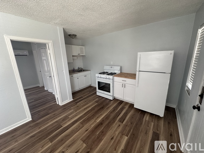 A kitchen with white appliances and wooden floors.