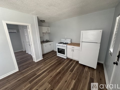A kitchen with white appliances and wooden floors.