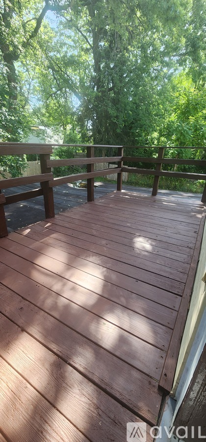 A wooden deck with a railing and trees in the background.