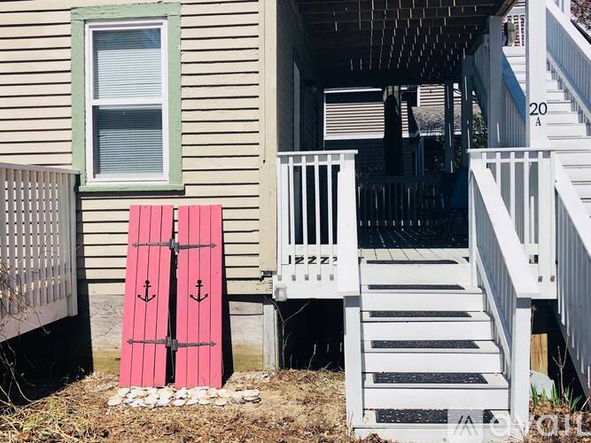 A pink door with two anchors on it is in front of a house.