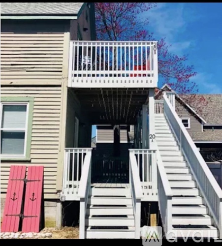 A house with a white deck and stairs leading to a basement.