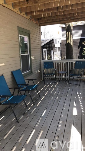 A wooden deck with blue chairs and a white railing.