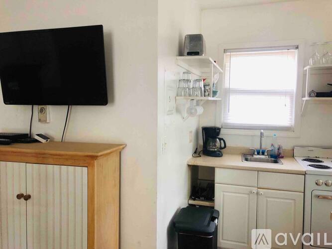 A small kitchen with a wooden cabinet and a black television.