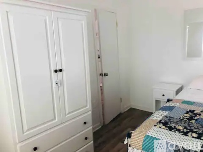A bedroom with a bed, dresser, and wardrobe.
