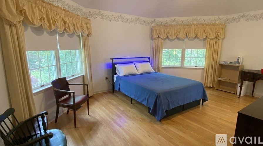A bedroom with a bed, chair, and window.