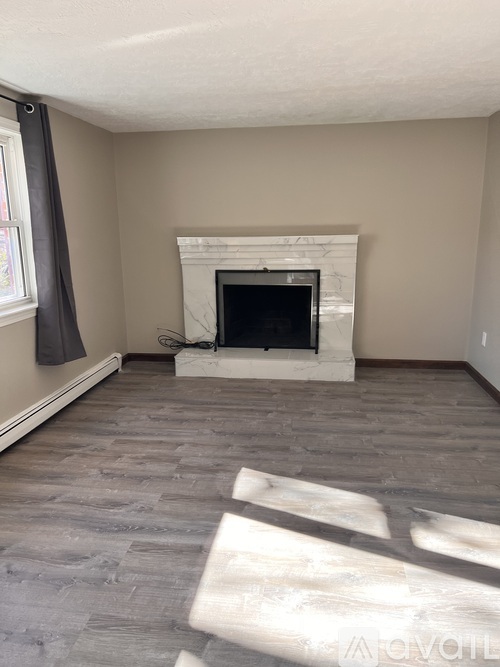 A living room with a fireplace and grey flooring.