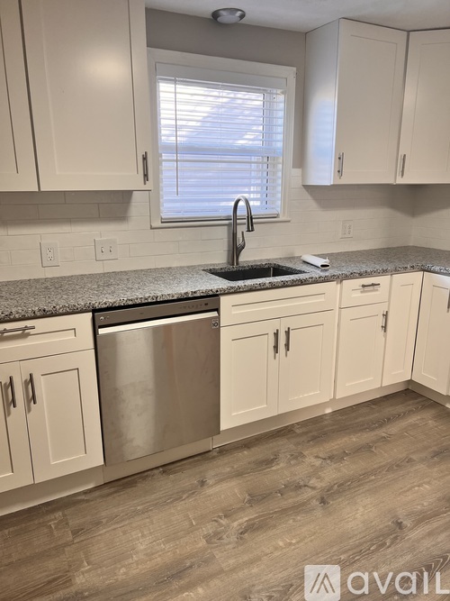 A kitchen with white cabinets and a stainless steel dishwasher.