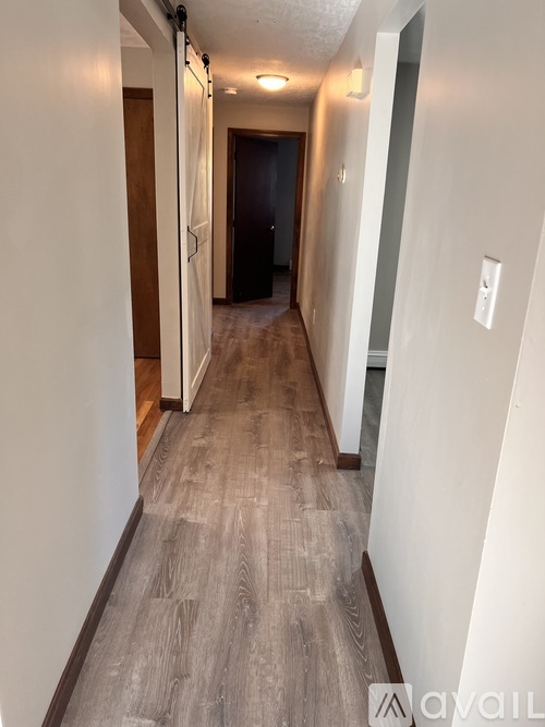 A long hallway with wood floors and white walls.