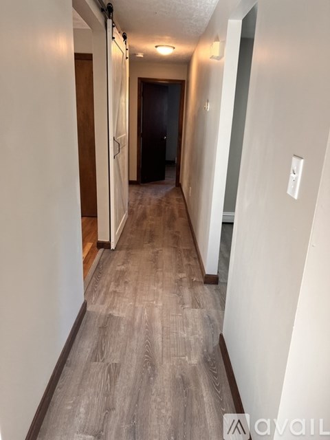 A long hallway with wood floors and white walls.