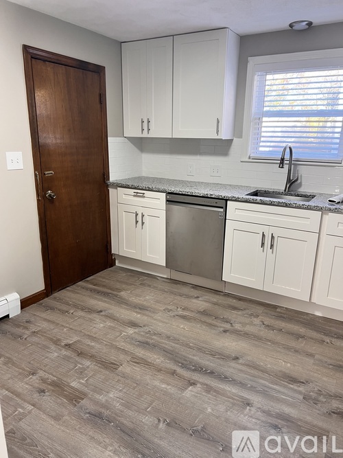A kitchen with a wooden door, white cabinets, and a granite countertop.