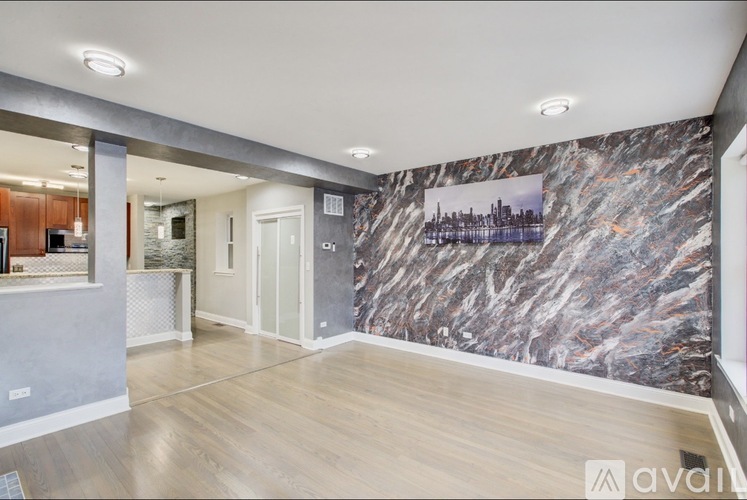 A spacious room with a marble wallpaper and wooden flooring.