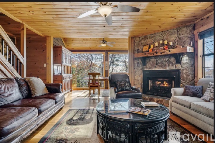 A living room with a stone fireplace and a ceiling fan.