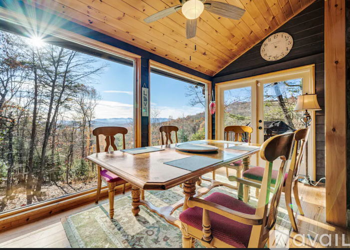 A sunny day in a wooden cabin with a table and chairs.