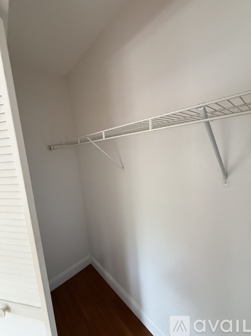 A white closet with a shelf and a white door.