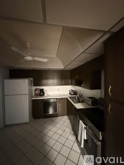 A kitchen with a white fridge, black countertops, and a fan on the ceiling.