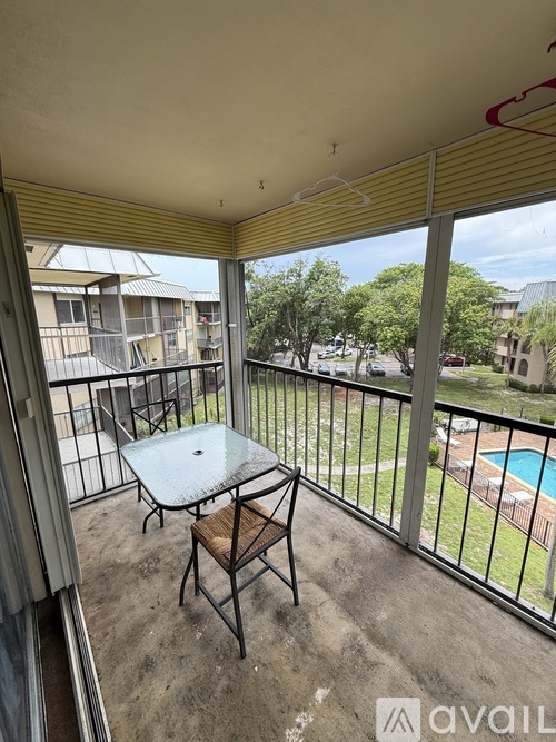 A balcony with a table and chairs overlooking a pool.