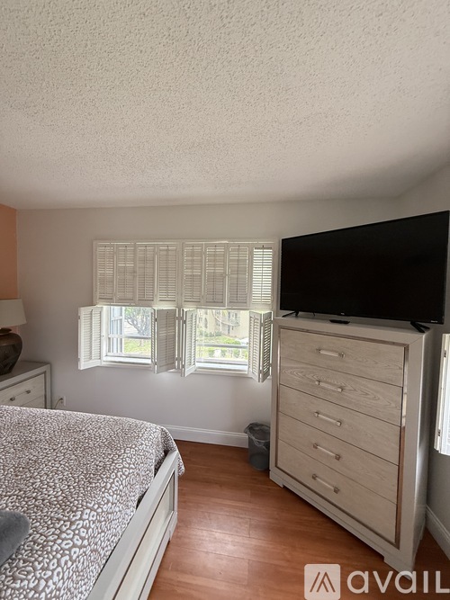 A bedroom with a bed, dresser, and window with blinds.