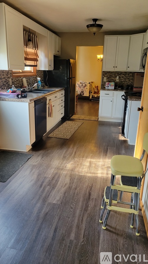 A kitchen with a black fridge and a yellow chair.