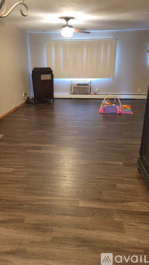 A room with wooden flooring and a window with blinds.