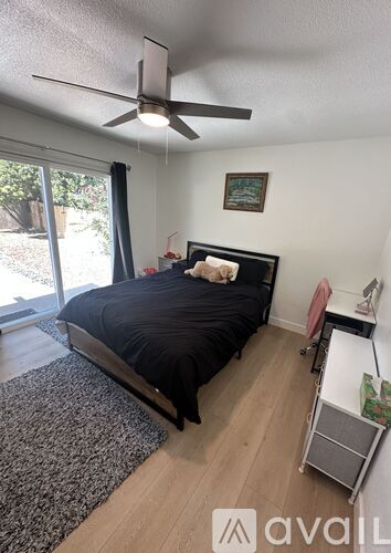 A bedroom with a bed, a fan, and a window.