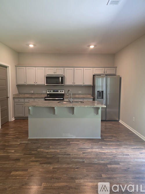A kitchen with a white island and stainless steel appliances.