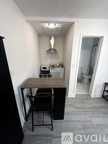 A kitchen with a table and chairs in the foreground and a microwave and oven in the background.