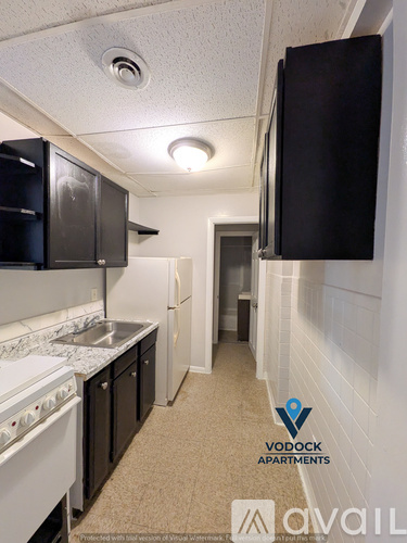 A kitchen with a white stove top oven and black cabinets.