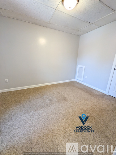 A carpeted room with Vodock Apartments logo on the floor.