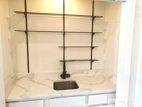 A white kitchen with a sink and shelves.