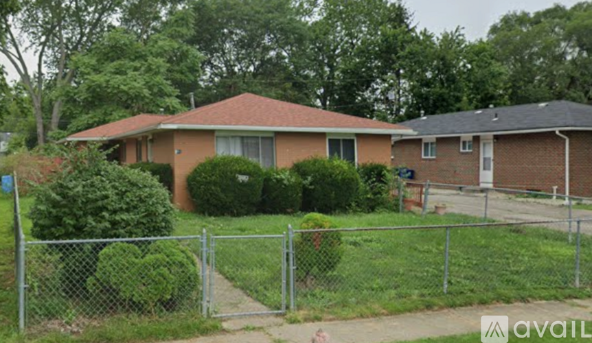 A house with a red roof and a fence in front of it.