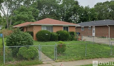 A house with a red roof and a fence in front of it.