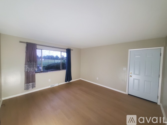 A room with a white door and a window with a view of the outdoors.