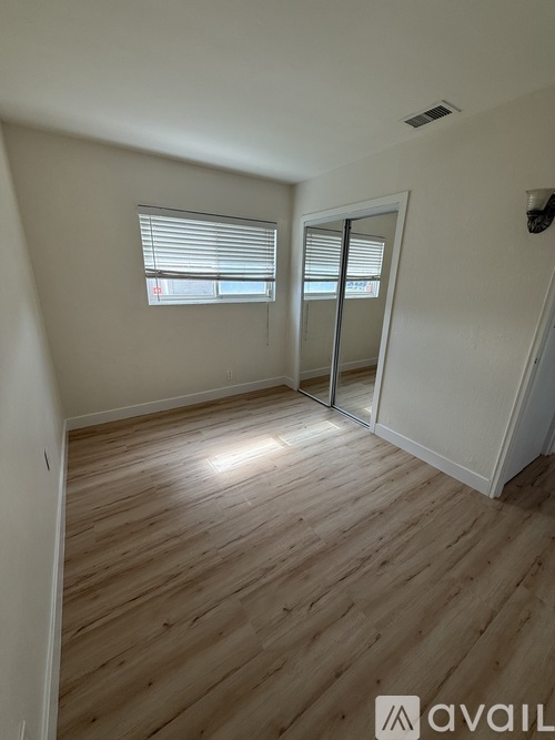 A room with wooden flooring and a window with blinds.